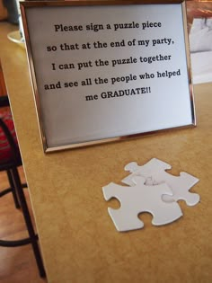 a piece of puzzle sitting on top of a wooden table next to a sign that says, please sign a puzzle piece so that at the end of my party