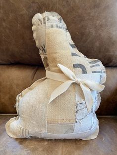 a pile of pillows sitting on top of a couch next to a pillow with a bow