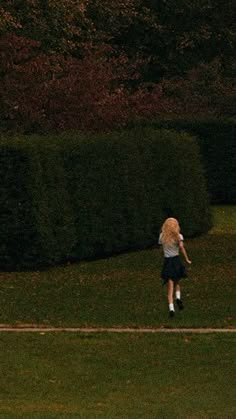 two people are playing frisbee in the grass near some bushes and trees at night