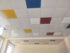 an empty room with white walls and multicolored tiles on the ceiling above it