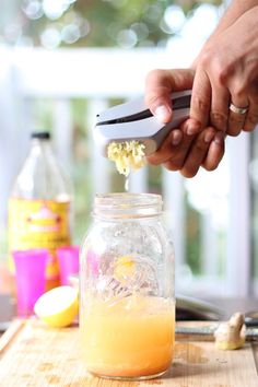 a person using a knife to cut up food in a mason jar on a cutting board