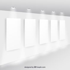 an empty white room with five blank canvases on the wall and lights above it