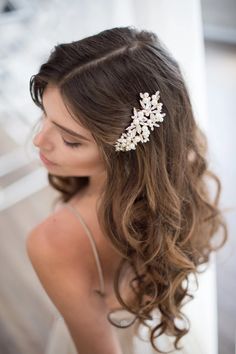 a woman wearing a hair comb with flowers on it's head and long curly hair