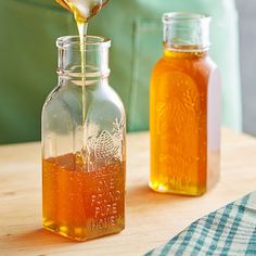 a person pouring honey into two glass jars