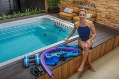 a woman sitting on the edge of a hot tub next to diving gear and equipment