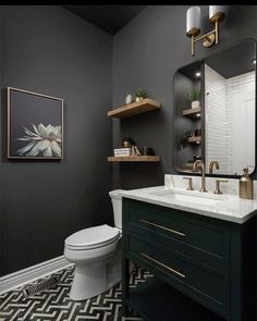 a white toilet sitting under a bathroom mirror next to a black and white tiled floor