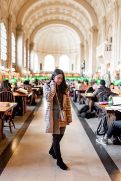 a woman is talking on her cell phone while standing in the middle of a library