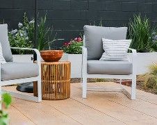 two white chairs sitting on top of a wooden deck