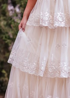 a woman in a white dress is holding her hand out to the side while wearing a veil