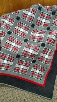 a blanket is laying on the floor next to a bed with a black and red plaid design