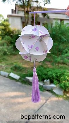 a paper flower hanging from a string with tassels