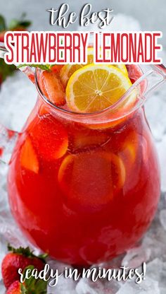 a pitcher filled with red liquid and sliced lemons on top of ice next to strawberries