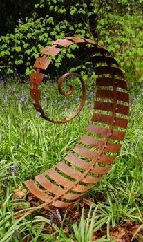 a metal sculpture in the middle of some grass