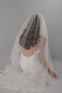 a woman wearing a wedding veil with pearls on it