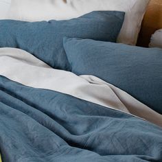 an unmade bed with blue sheets and pillows