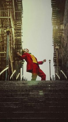 a man dressed in red and yellow is walking up some stairs with his arms outstretched