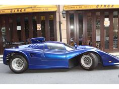 a blue sports car parked in front of a building