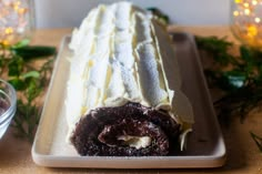 a chocolate cake with white frosting on a platter next to some christmas decorations