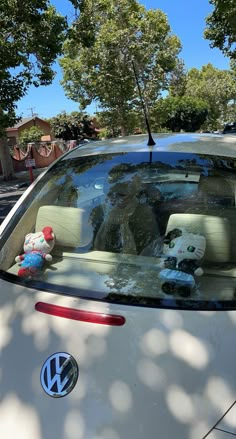 the back window of a white car with stuffed animals in it's passenger seat