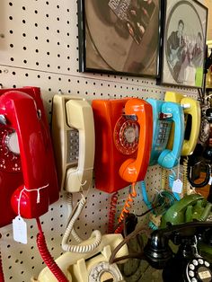 an assortment of telephones are on display in a store with pictures hanging above them