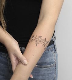 a woman with a flower tattoo on her left arm holding onto the other arm,