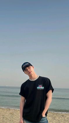 a boy standing on the beach with his skateboard