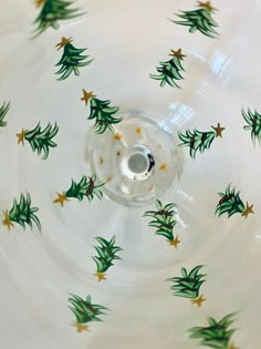 a white bowl with green and gold christmas trees on it's rim, surrounded by stars