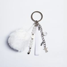 a keychain with some charms attached to it on a white surface, next to a feather