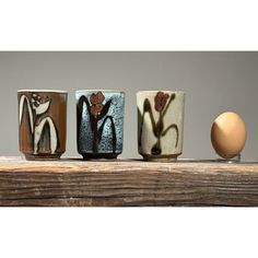 three vases sitting on top of a wooden table with an egg in the background