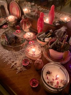 a table topped with lots of candles next to dishes filled with flowers and other items