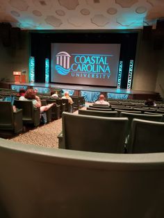 people are sitting in chairs at the front of an auditorium