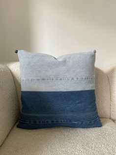 a blue and white striped pillow sitting on top of a couch next to a wall