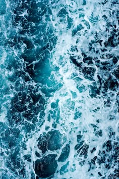 an aerial view of the ocean waves and rocks