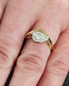 a close up of a person's hand wearing a ring with a diamond on it