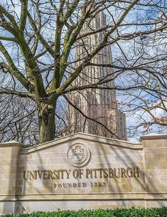 the university of pittsburgh sign in front of a tree and building with a clock tower