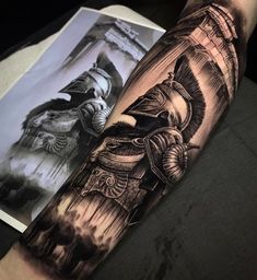 a man's arm with tattoos on it and an image of a statue in the background