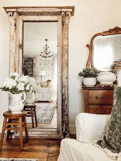 a mirror sitting on top of a wooden floor next to a white chair and table