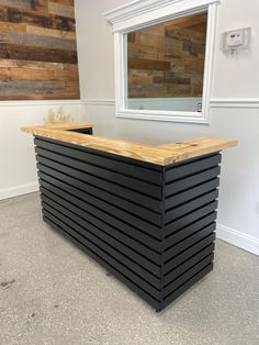 a counter made out of black slats in front of a wooden wall with a mirror above it