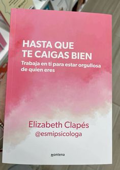 a person holding up a pink book in their hand with spanish writing on the cover