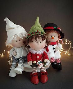 three small christmas figurines sitting next to each other on a black surface with lights in the background