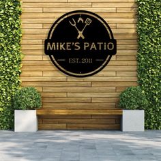 the sign for mike's patio is shown in front of a wooden wall and planters