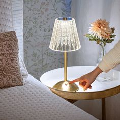 a table with a lamp on it and a person reaching for something in the bowl