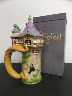 a ceramic mug with a castle on it next to a box