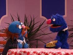 the sesame street characters are talking to each other in front of a table with a red checkered tablecloth