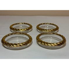 four glass dishes with gold rims on a white table