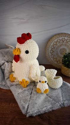 a crocheted chicken sitting on top of a table next to two smaller chickens