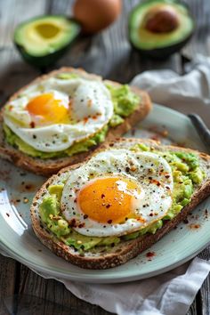 two pieces of bread with an egg on top and avocado in the background