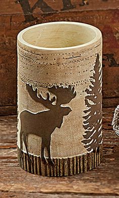 a cup with a moose on it sitting next to a teddy bear and wooden planks