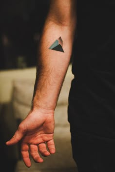 a man's arm with a small triangle tattoo on it