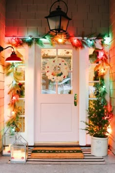 the front door is decorated with christmas lights and garlands, including pineconi